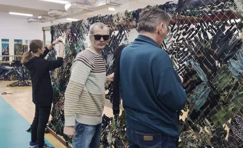 НЕЗРЯЧІ ВОЛОНТЕРИ-ЧОЛОВІКИ ПЛЕТУТЬ МАСКУВАЛЬНІ СІТКИ ДЛЯ ДОПОМОГИ АРМІЇ
